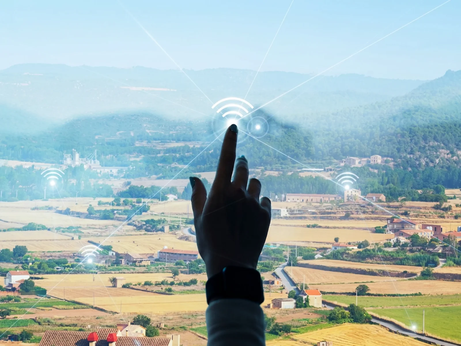 Mano señalando un icono de conectividad sobre un paisaje rural